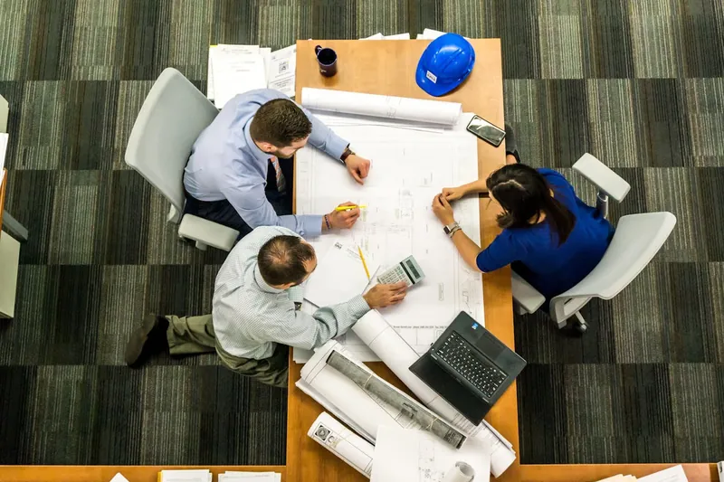 Engineers around a table reviewing drawings